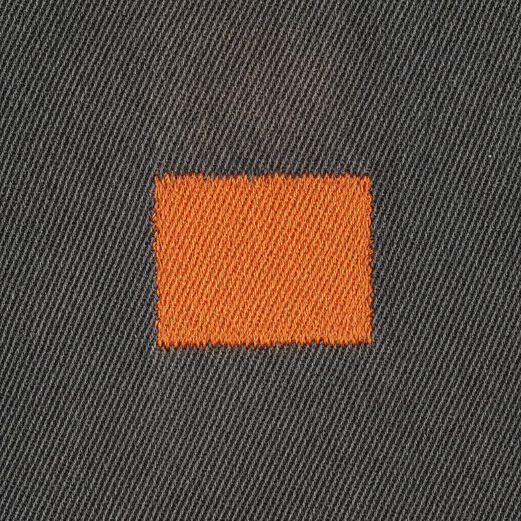 Macro of dense orange satin stitching on heavy dark twill